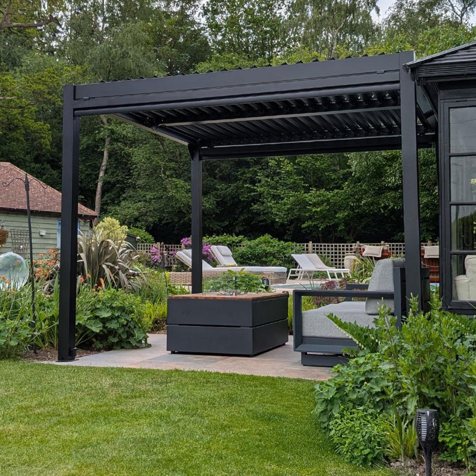 Black aluminium pergola in a private pool garden, summer afternoon